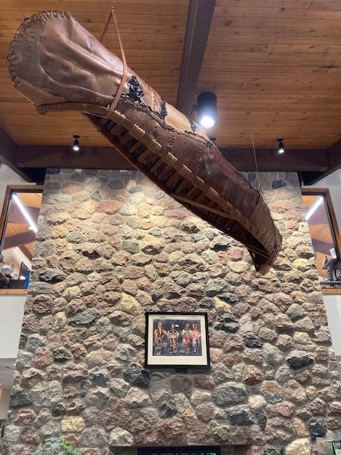 photo of a traditional canoe hanging from the ceiling. The canoe is made of wood and rawhide.