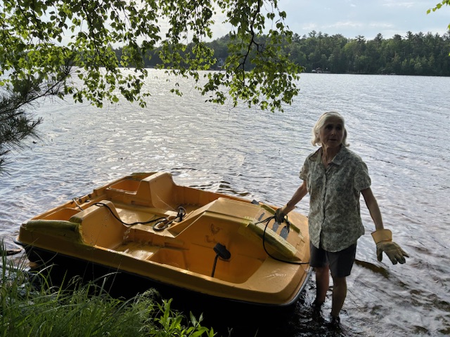 photo of woman standing in lake next to paddle boat