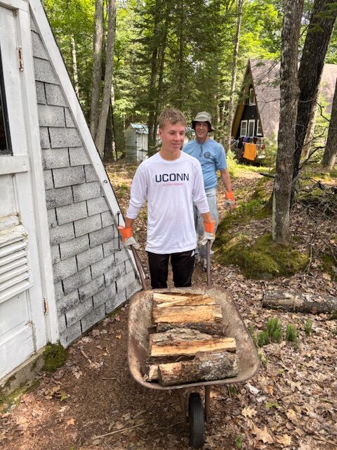 boy and man using a wheelbarrow to transport wood