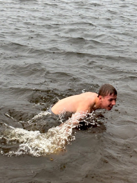 boy getting out of the lake when it's raining.